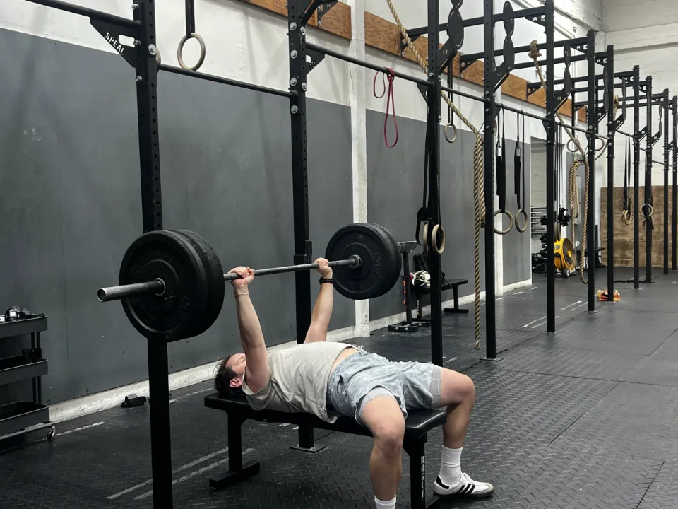 A client bench pressing a barbell during a personal training session