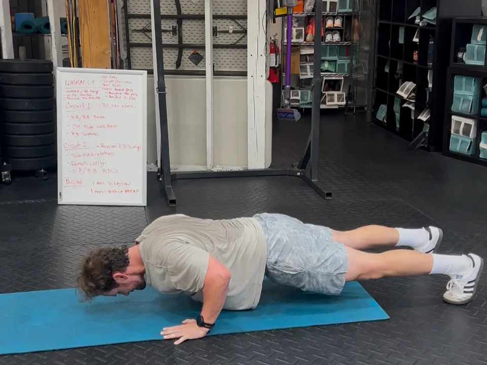 A client doing push-ups, with the session plan on a whiteboard behind him